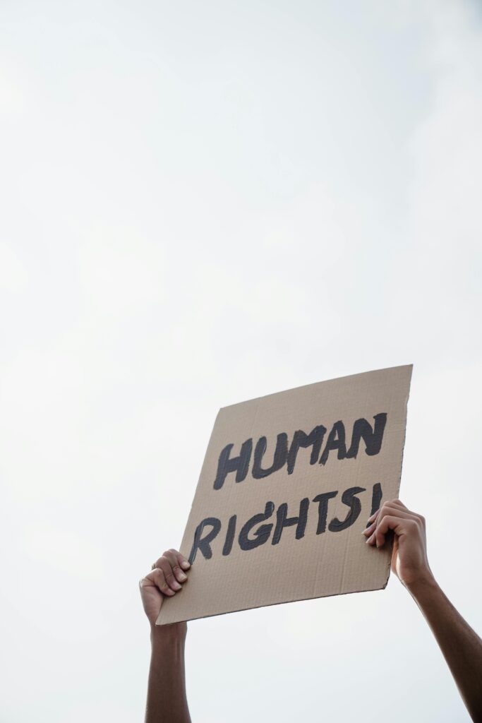 A close-up of a human rights protest sign held up against the sky.